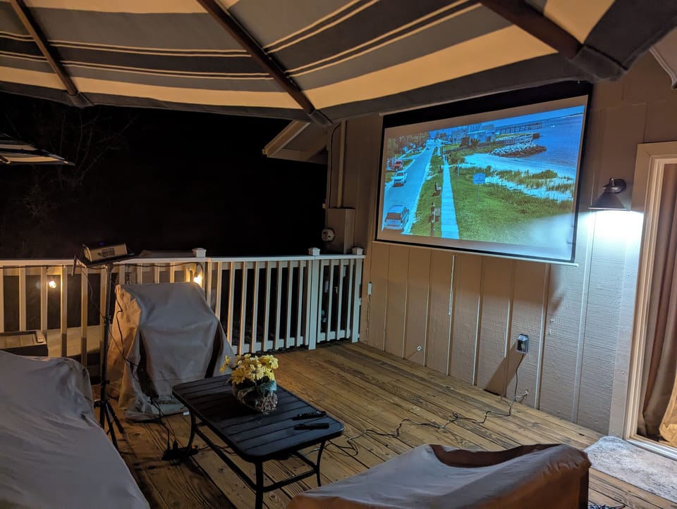 Covered deck outdoor movie theater with projector at night