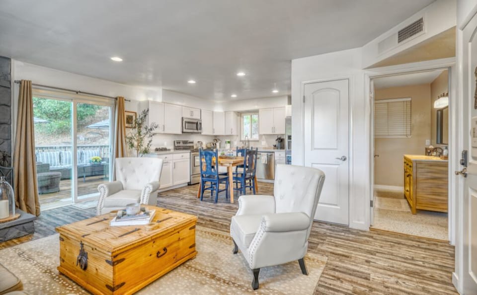 Open living room and full kitchen with deck access and forest views