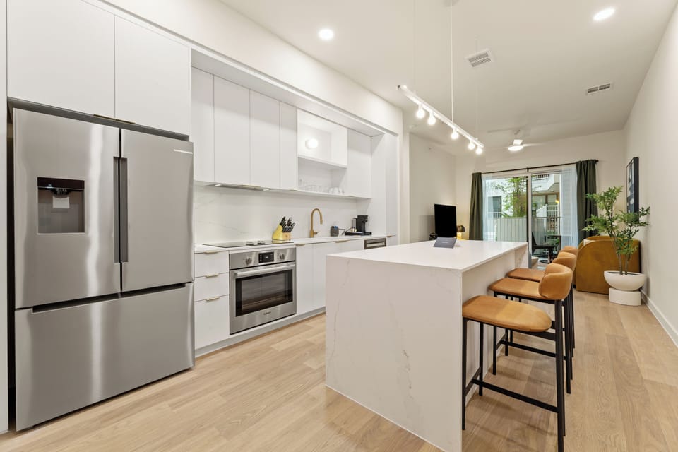 Cook, gather, and unwind in this bright modern kitchen featuring sleek finishes, stainless steel appliances, and island seating for the whole group.