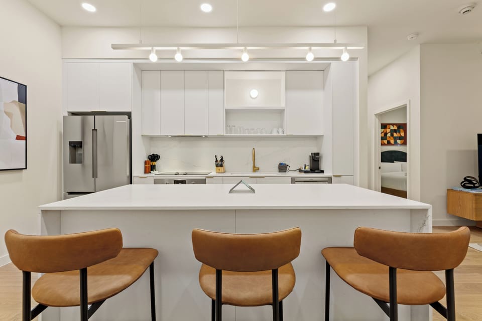 Cook, gather, and unwind in this bright modern kitchen featuring sleek finishes, stainless steel appliances, and island seating for the whole group.