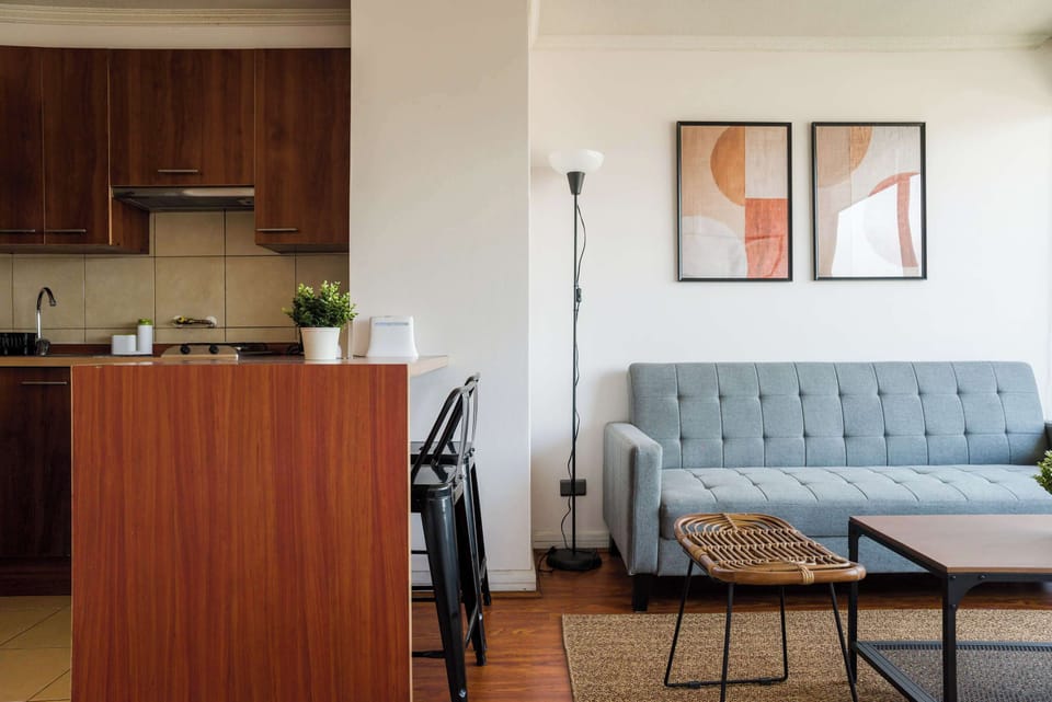 Stylish living area with a cozy sofa and functional kitchen, perfect for relaxation and comfort.