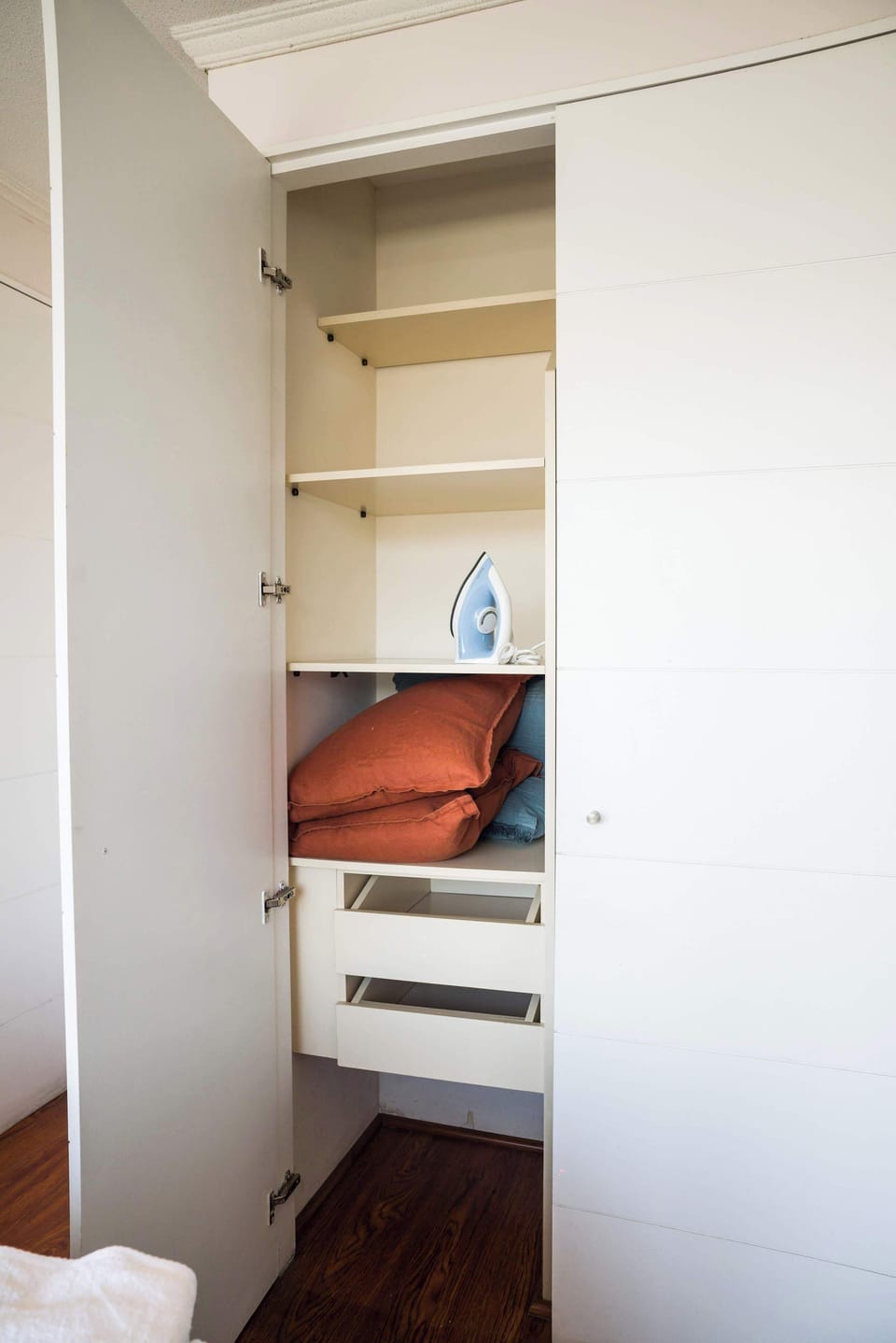 Well-organized closet with essentials like an iron and extra pillows ensures a comfortable stay.