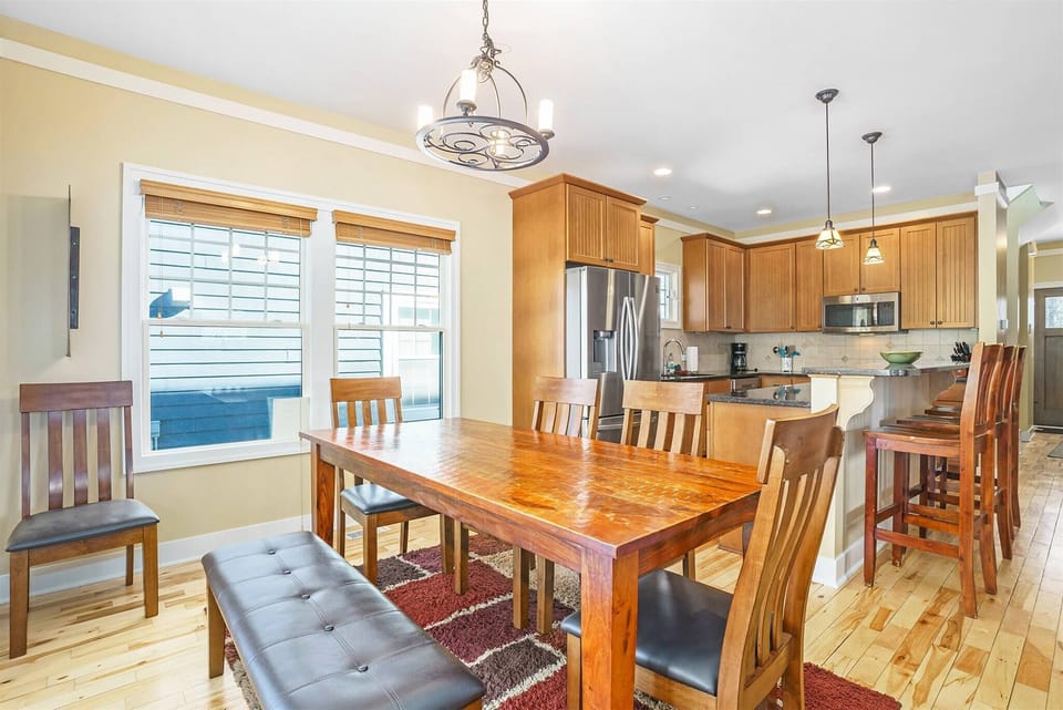 Dining area with a large wooden table and bench seating, opening into a spacious kitchen