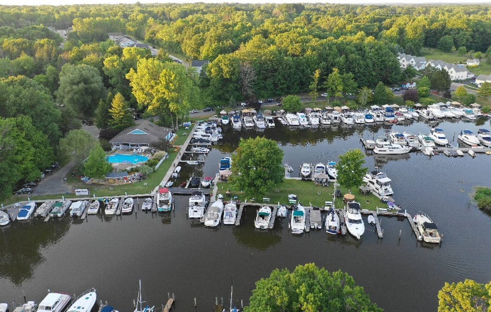 Stunning aerial view of the Woodland Harbor marina and surrounding nature, home to Blue water Boat Rentals. Guests can explore the water with ease or relax by the seasonal pool.