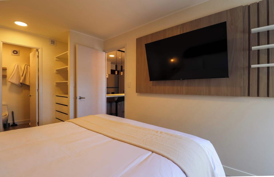 Comfortable bedroom featuring a wall-mounted TV and a clean, modern design.