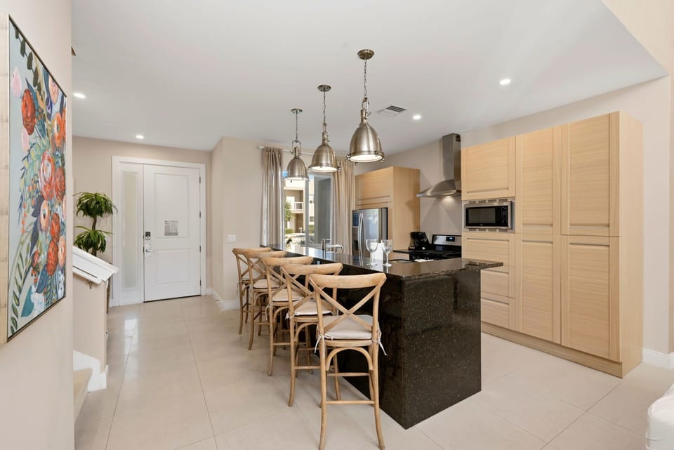 Modern kitchen with a large black granite island and wooden bar stools for casual dining.