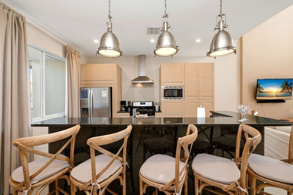 Modern kitchen with a black granite island and wooden bar stools for casual dining.