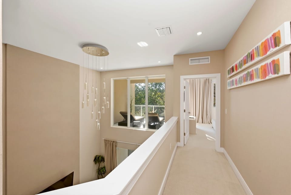 Bright hallway with modern pendant lighting and a view of the outdoor seating area.