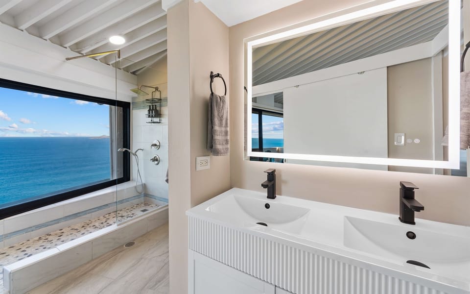 The ensuite bathroom has double sinks and a walk in shower with a view