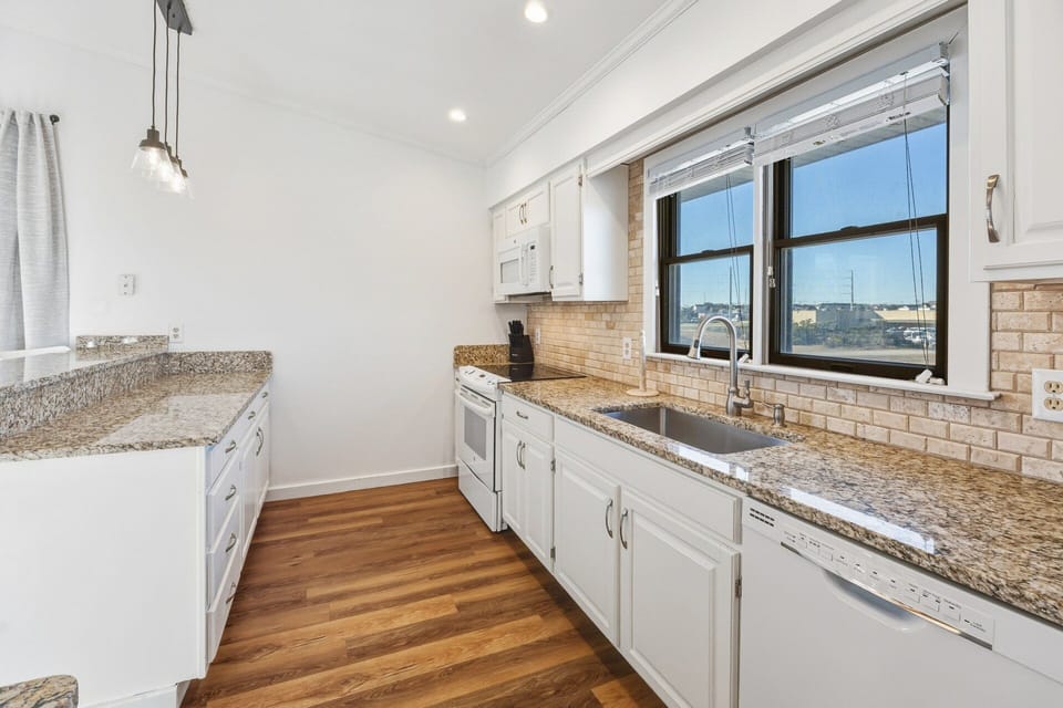 The fully equipped kitchen features granite countertops and a breakfast bar for casual meals or morning coffee.