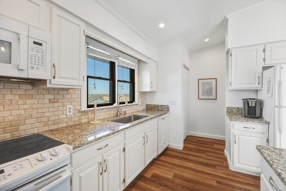 The fully equipped kitchen features granite countertops and a breakfast bar for casual meals or morning coffee.