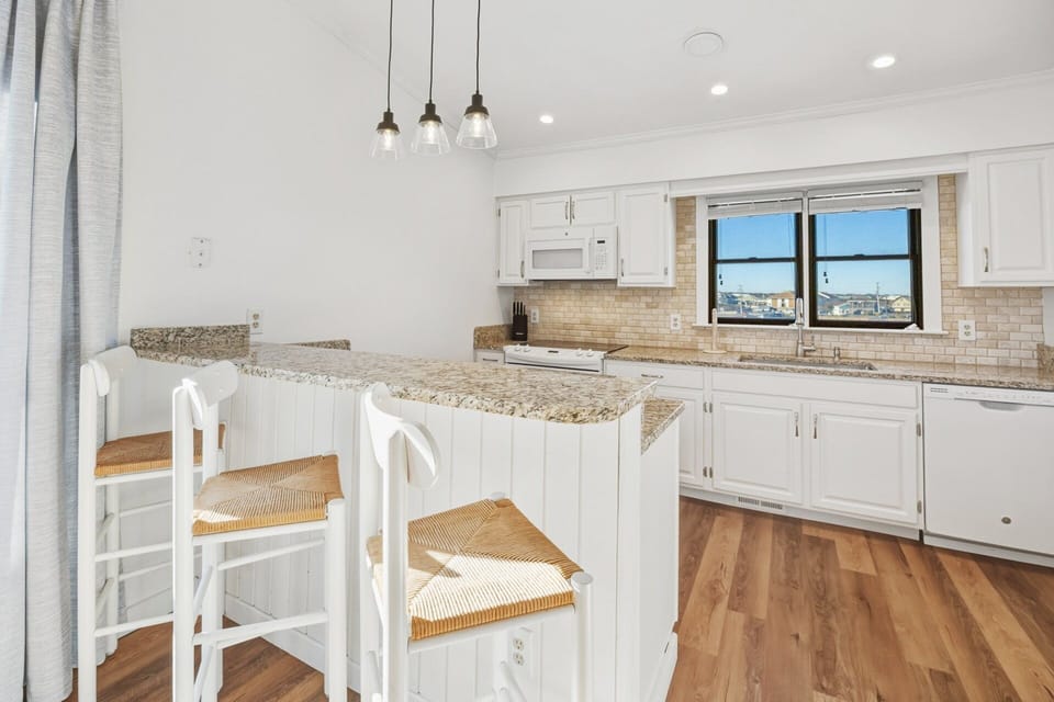 The fully equipped kitchen features granite countertops and a breakfast bar for casual meals or morning coffee.