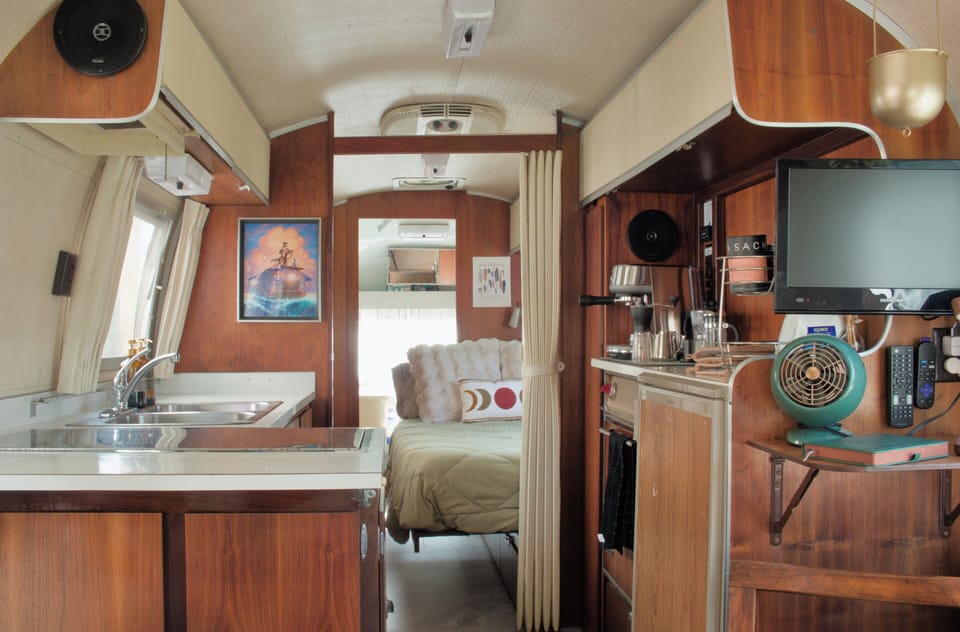 Cozy vintage camper with kitchenette, TV, and inviting bed nook