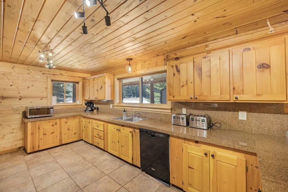 Spacious kitchen with rustic cabinetry, modern appliances, and forest views.