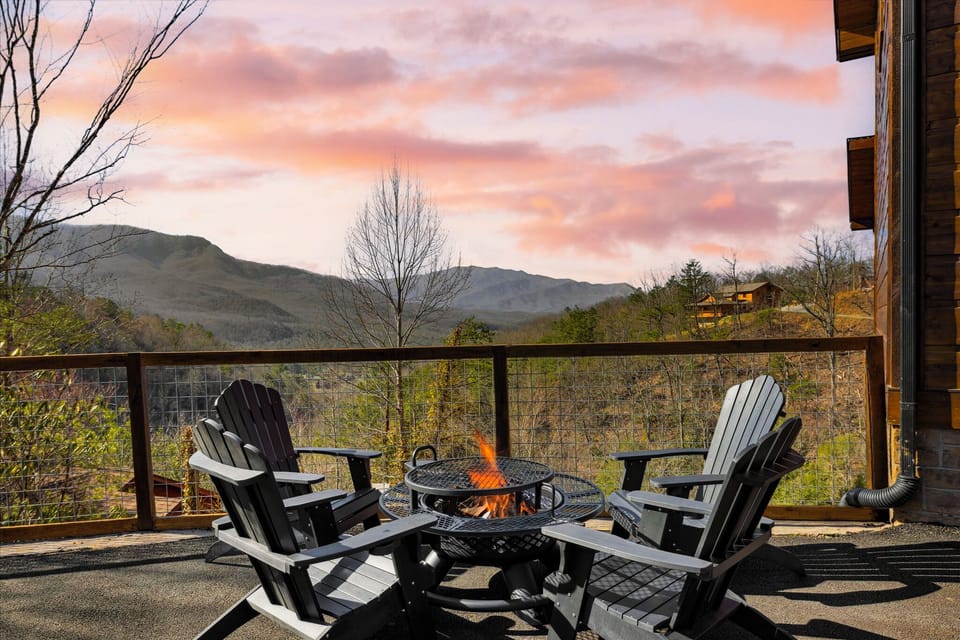 Adirondack chairs surrounding a fire pit on the deck with mountain views.