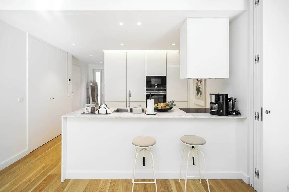 Open-plan kitchen with white cabinetry, a large island with bar stools, and stainless steel appliances. Perfect for cooking and entertaining, with plenty of counter space and natural light.