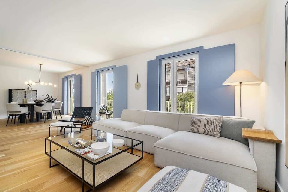 Bright, elegant and design living room with a large, comfortable sofa, glass coffee table, and dining area. Natural light streams through large windows, creating a warm atmosphere! 