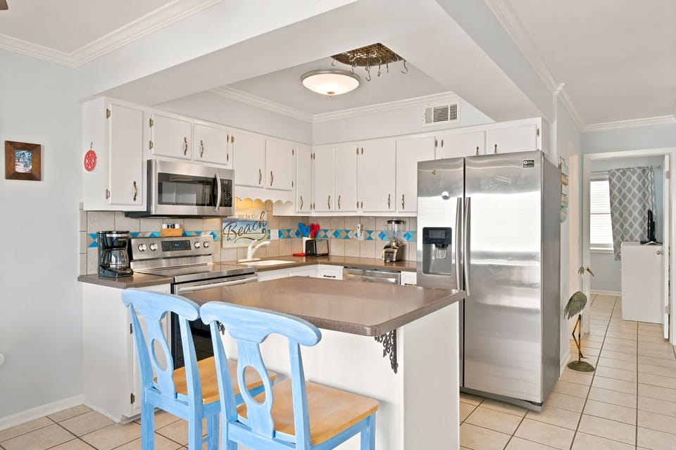 Your bright, fully equipped kitchen features modern stainless steel appliances and a welcoming breakfast bar where you can sip morning coffee before heading to the beach.