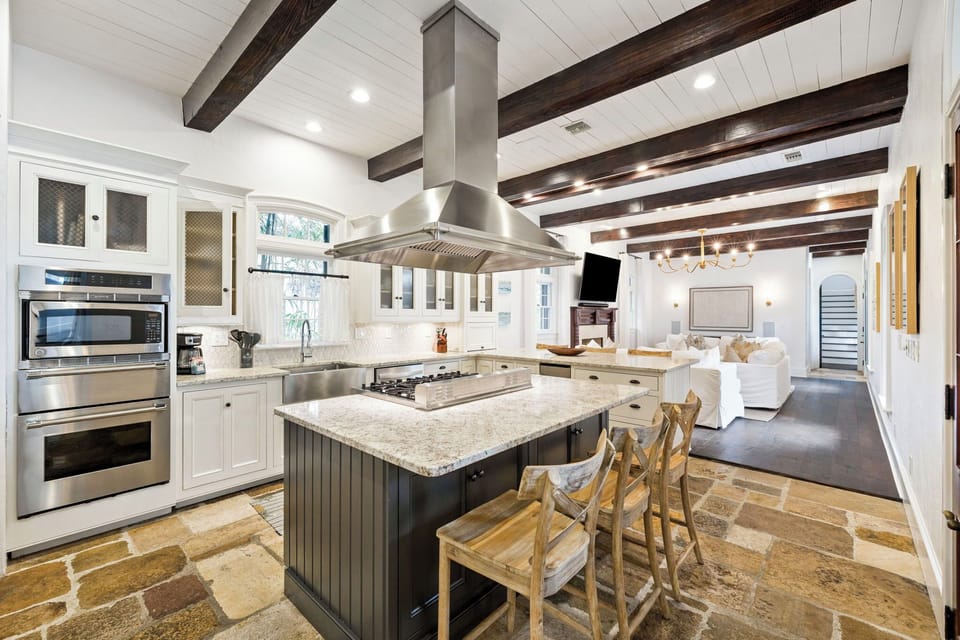 You'll love cooking in this stunning gourmet kitchen featuring exposed beams, granite counters, and professional-grade appliances beneath soaring ceilings.