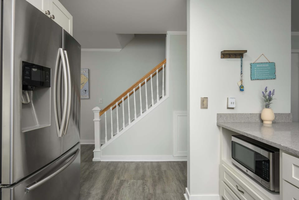 Modern kitchen area featuring stainless steel appliances and a view of the stairs.