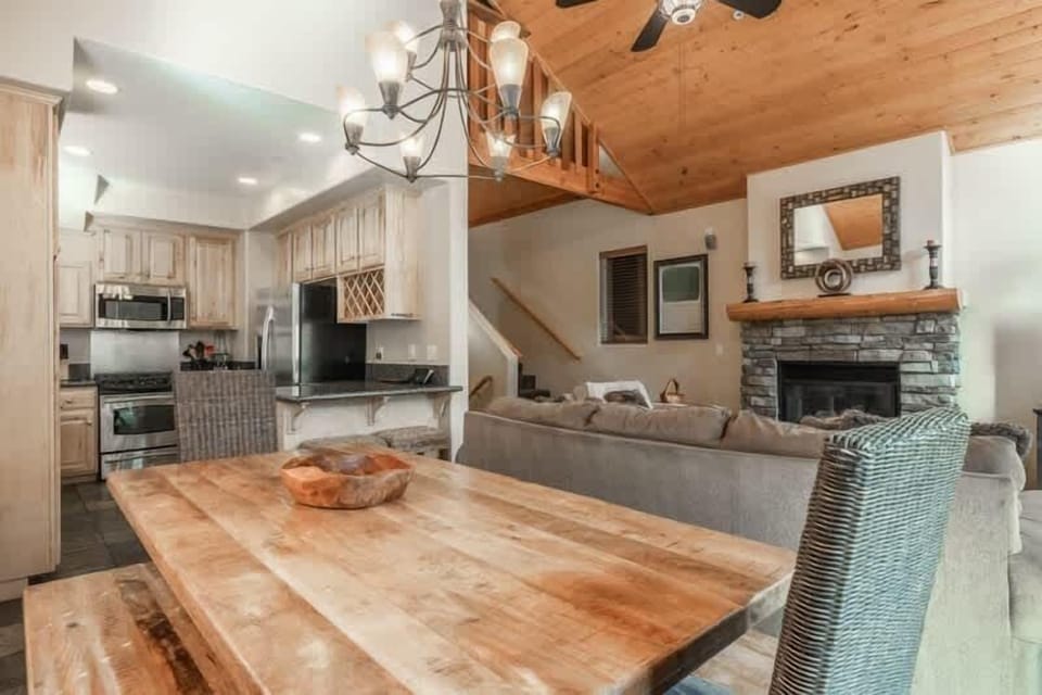Bright dining area with a large wood table, bench seating, and modern chandelier.
