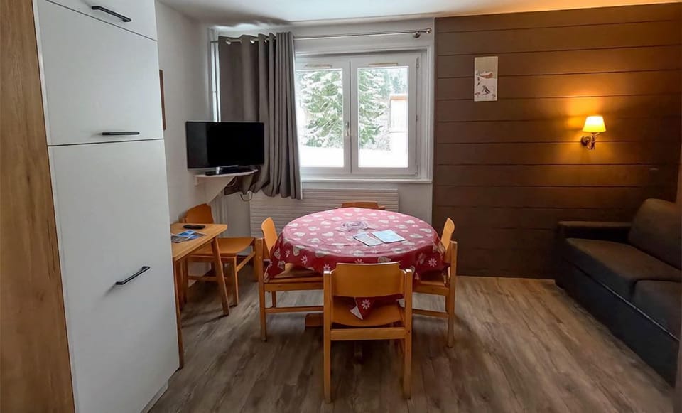 This inviting dining area features a cozy round table, perfect for family meals, accompanied by a comfortable sofa and large windows that overlook the snowy landscape.