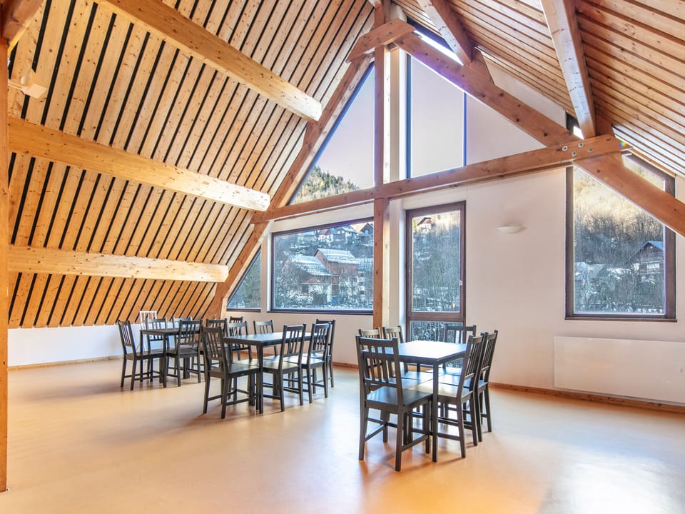 Brightly lit with expansive windows, this spacious gathering spot blends rustic charm with breathtaking views of the surrounding alpine landscape.