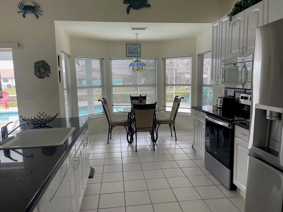 Open-concept kitchen and dining area with large windows overlooking the pool and outdoor space