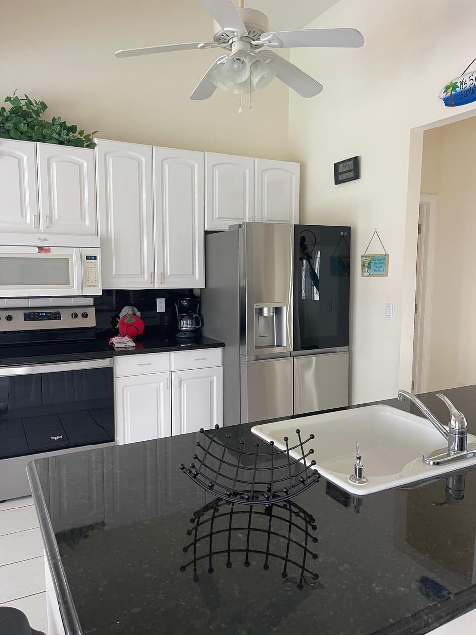 Kitchen featuring stainless steel appliances, large island with dark granite countertop, and tile flooring