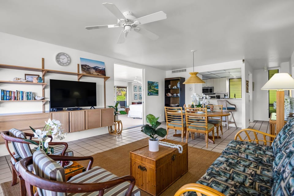 An inviting open‑concept living, dining, and kitchen area designed with tropical textures and an airy island ambiance