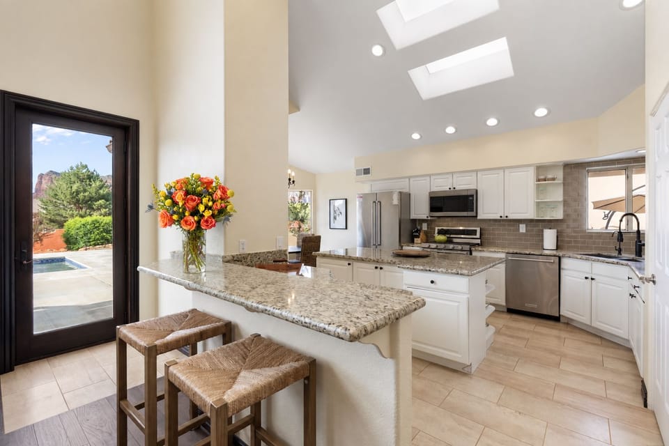 Bright gourmet kitchen with skylights, granite island, and pool views