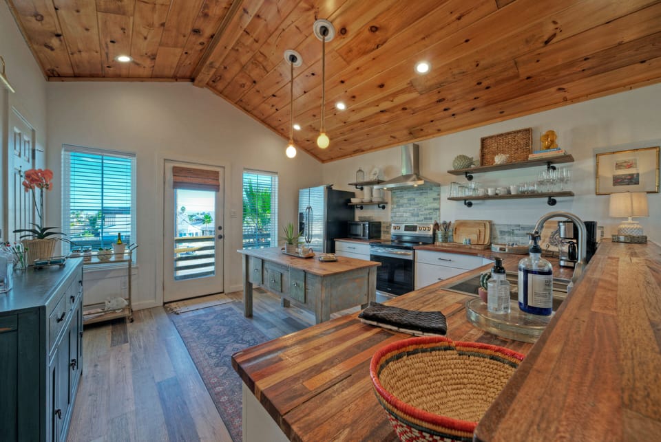 Bright, coastal-inspired kitchen with warm wood finishes—perfect for casual breakfasts, sunset cocktails, and gathering with friends.