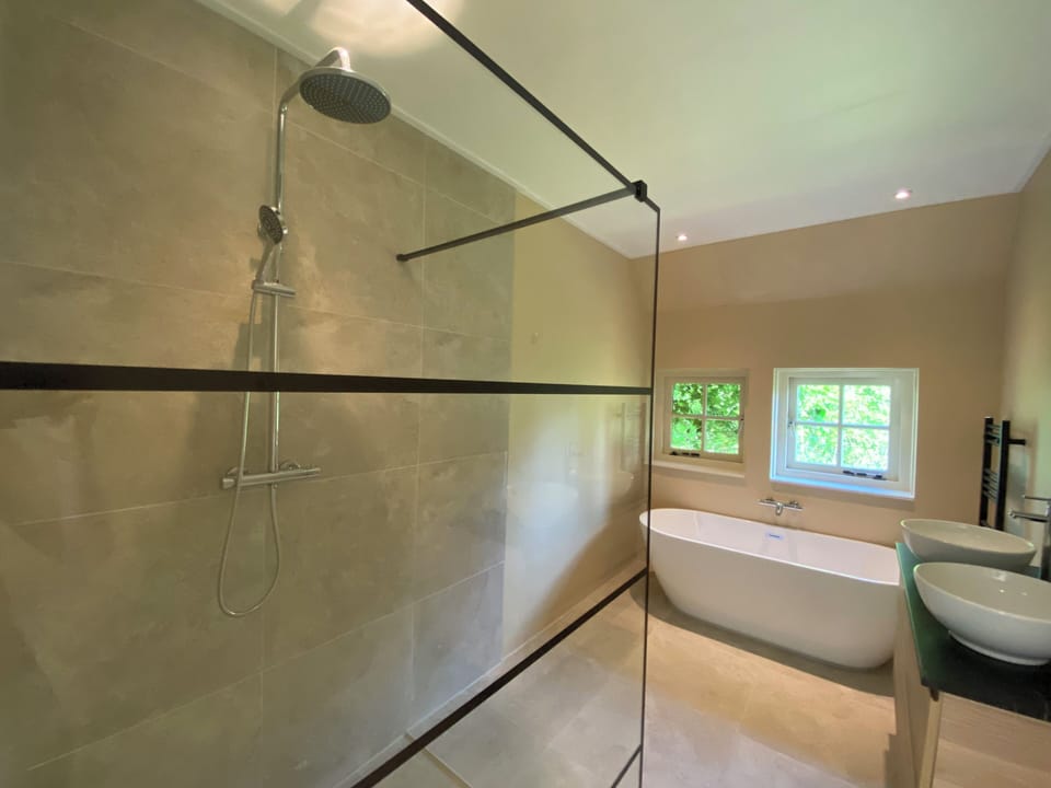 Bathroom with a bath and rain shower. Towels are provided