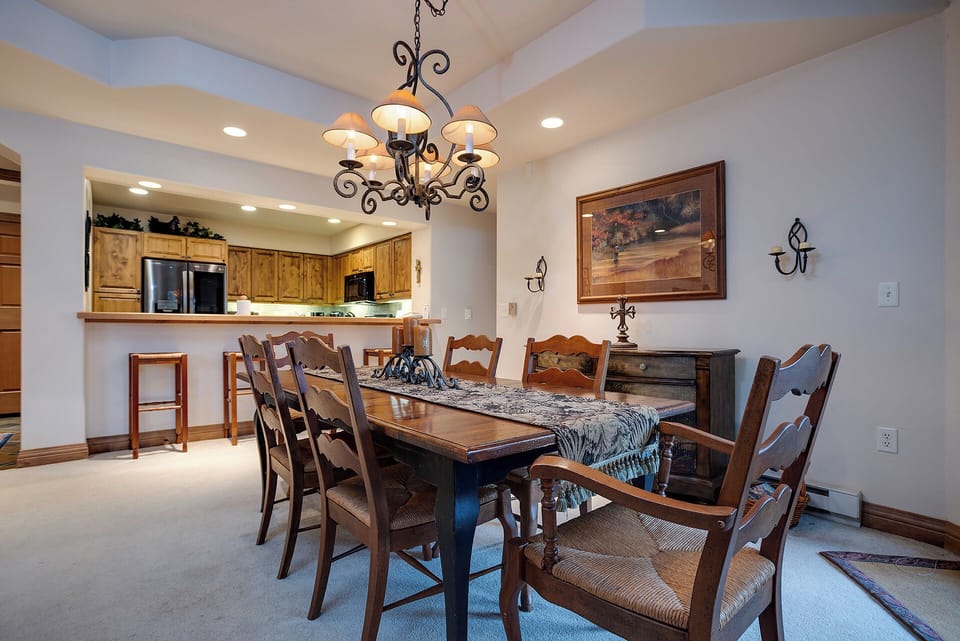 Gather around this elegant dining table for memorable meals with your group, featuring warm wood tones and a charming chandelier overhead.