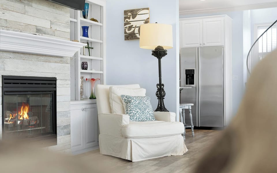 Curl up in your cozy reading chair beside the crackling fireplace, where coastal charm meets comfort in this beautifully designed living space.