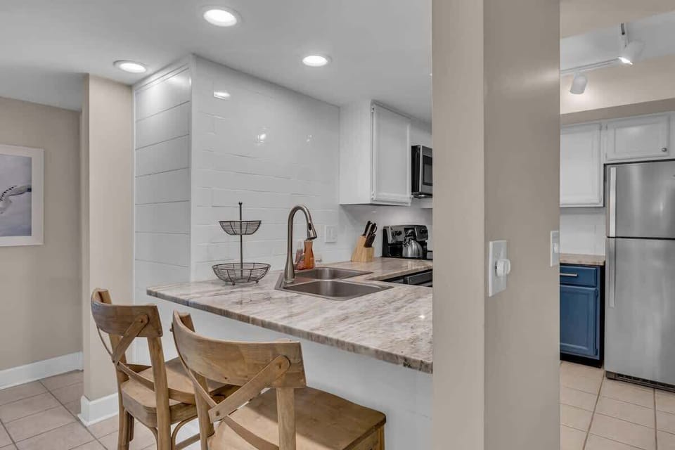 Your sleek kitchen features marble countertops and modern appliances, perfect for preparing meals and casual dining at the breakfast bar.