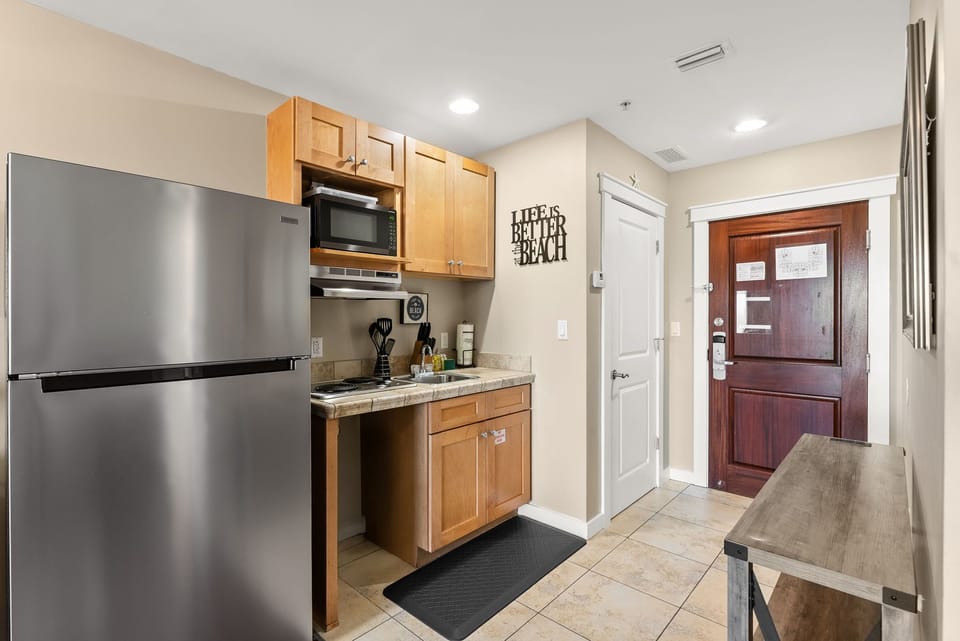 Your fully-equipped kitchenette features stainless steel appliances and warm wood cabinetry, perfect for preparing meals during your beach getaway.