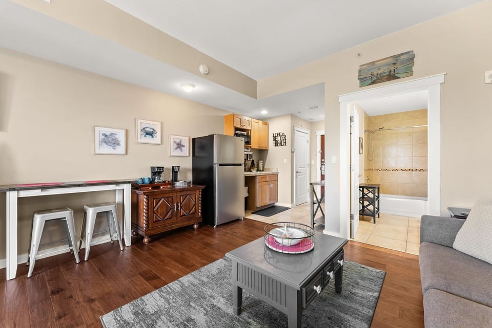 Your cozy open-plan suite blends kitchen, dining, and living spaces with warm hardwood floors and coastal touches throughout.