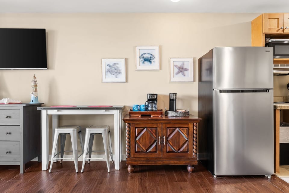 Your fully equipped kitchen awaits with stainless steel appliances, coffee station, and charming coastal artwork to start each morning perfectly.
