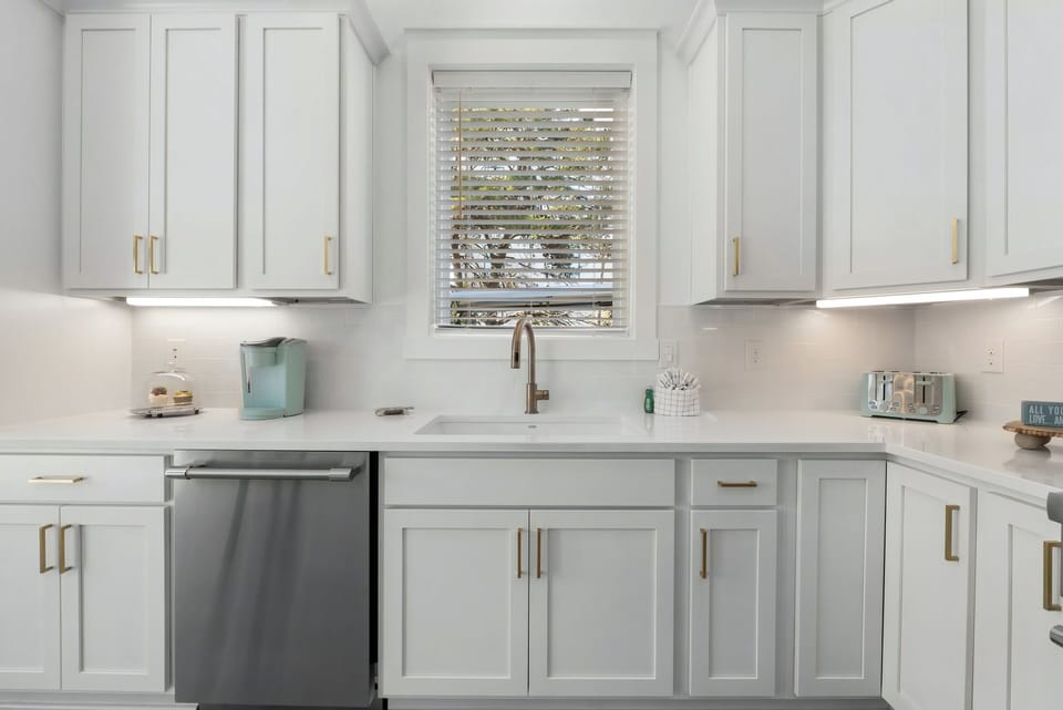 A charming kitchen with soft cabinetry and warm gold accents.