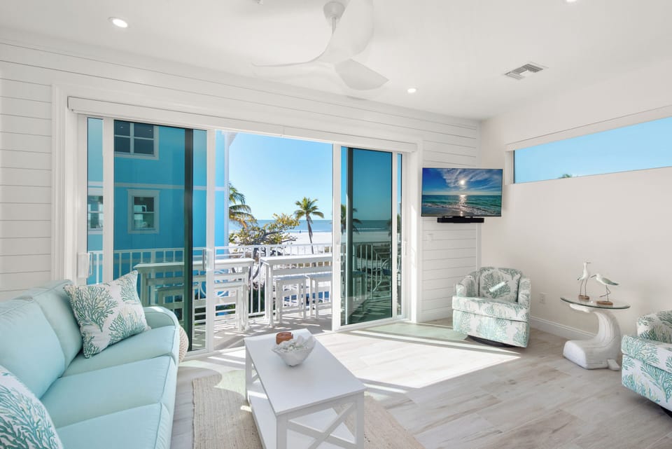 Living room area with sliding glass doors, outdoor furniture & beach views