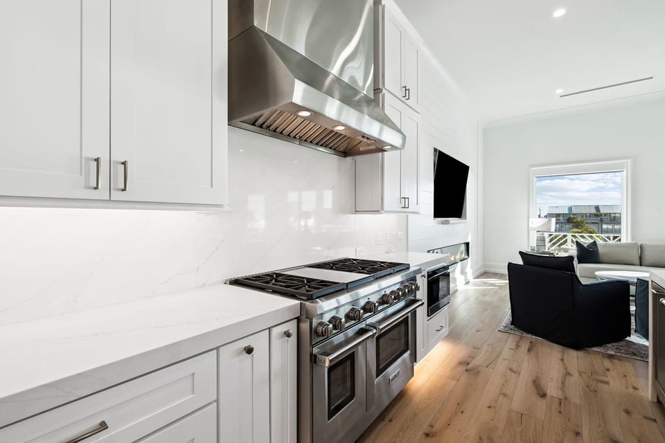 Your gourmet kitchen awaits with professional-grade appliances, pristine white cabinetry, and an open flow to the cozy living area.