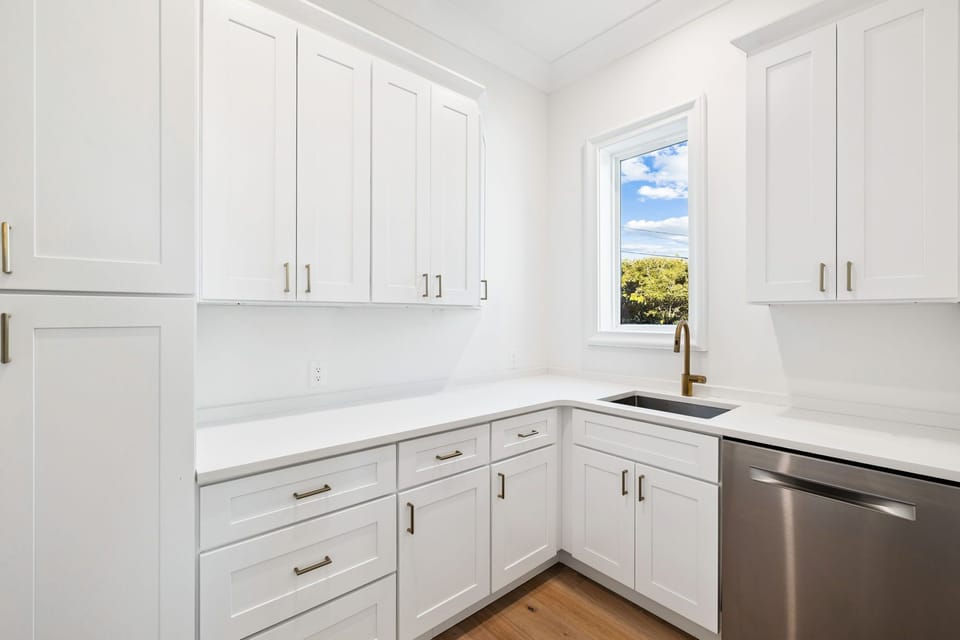 Your pristine white kitchen offers marble countertops, stainless appliances, and a bright window view for inspiring your culinary adventures.
