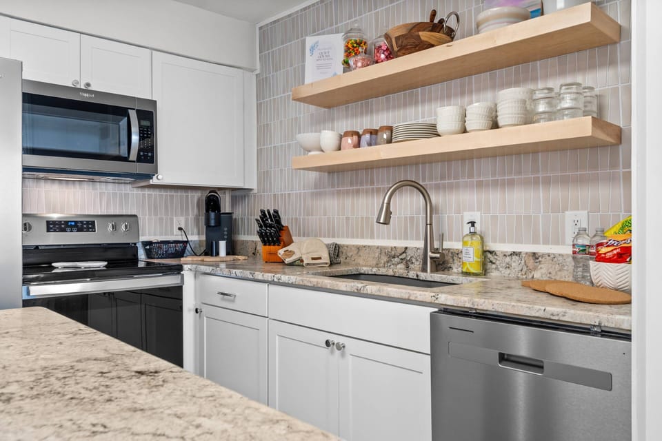 Modern kitchen workspace with open shelving, granite countertops, and updated fixtures