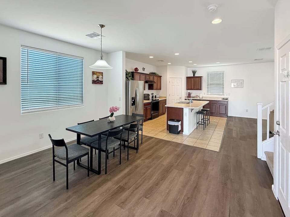 Dining area with table, chairs, window, and kitchen beyond