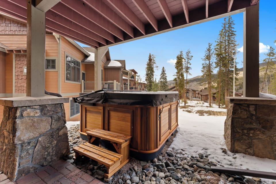 Your private hot tub awaits beneath a sheltered patio, framed by towering pines and mountain views—perfect for soaking away the day's adventures in crisp alpine air.