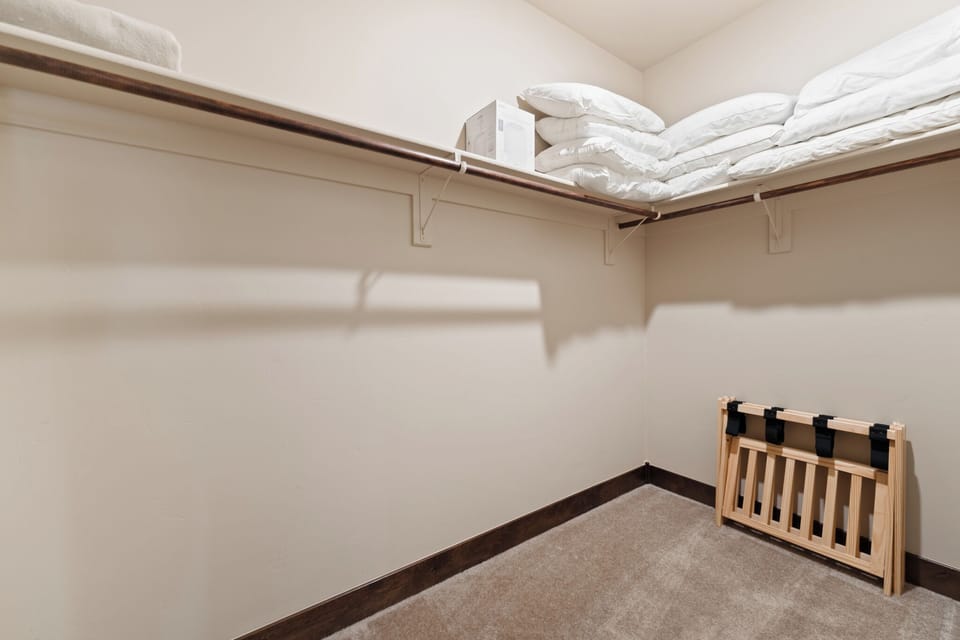Your spacious walk-in closet offers abundant storage with high shelving for linens and a convenient folding luggage rack for easy packing.