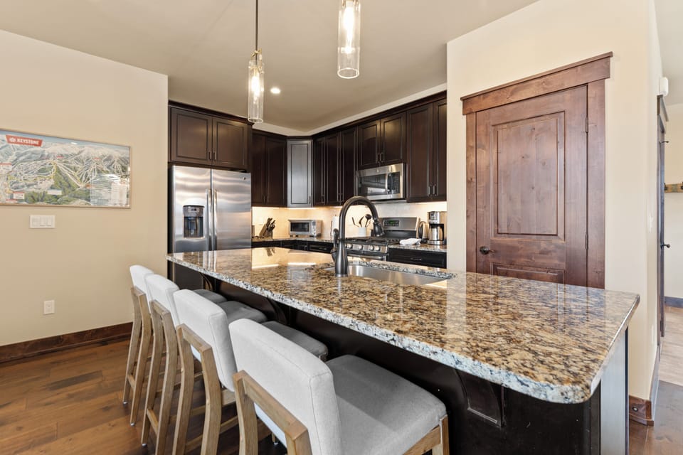 Gather around this spacious granite island, perfect for your morning coffee or preparing meals together in a kitchen designed for comfort and connection.