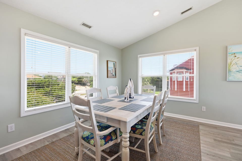 Gather around this inviting dining table with coastal views stretching through the windows. Soft natural light fills your space while you enjoy meals with loved ones in this serene setting.
