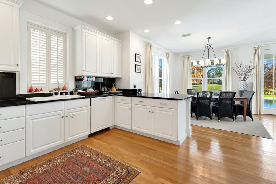 Cook your favorite meals in this bright, modern kitchen with white cabinets and dark countertops, then enjoy dining with lake views.